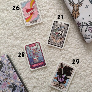 K&ouml;nnte beinhalten: Neun Tarot-Karten-Aufkleber mit bunten Illustrationen und Text. Die Karten sind von 26 bis 29 nummeriert. Die Karten zeigen Bilder von Liebenden, Feinden zu Liebenden, einem Tarotleser und einem vierten Fl&uuml;gel.