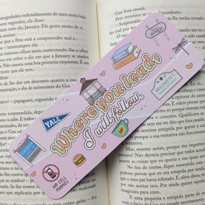 Op de afbeelding: Roze boekenlegger met de tekst "Where You Lead I Will Follow" en diverse illustraties, waaronder een prieel, een hamburger en een Yale wimpel. De boekenlegger ligt in een open boek.