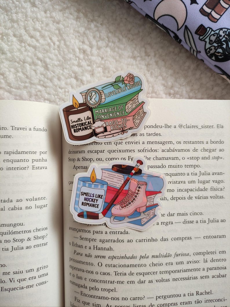 May include: Three colorful book-themed stickers with text that reads "Loveable Rogue", "Marriage of Convenience", and "Rags to Riches". The stickers also feature a rose, a candle, and a hockey stick with a pair of ice skates.