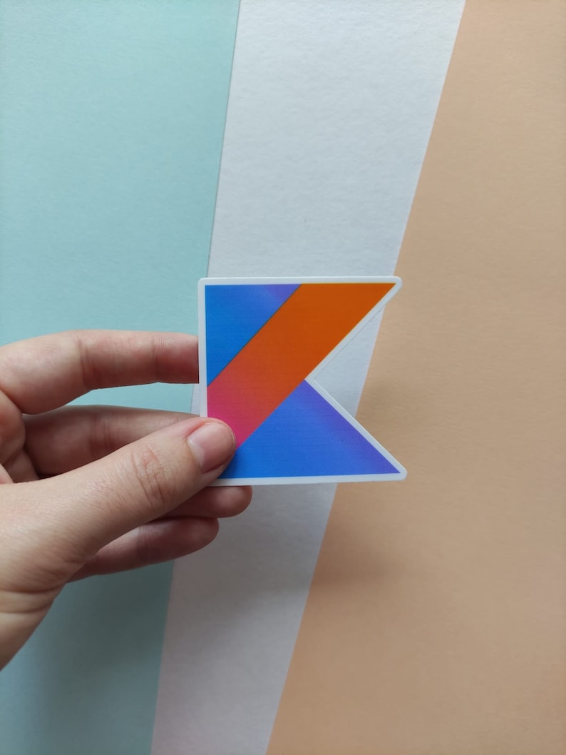 Peut inclure: Un autocollant repr&eacute;sentant le logo du langage de programmation Kotlin. Le logo est un K stylis&eacute; avec un d&eacute;grad&eacute; bleu, orange et rose.