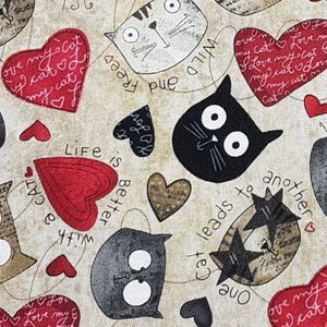 May include: A beige fabric with a repeating pattern of cats, hearts, and the phrase "Life is better with a cat". The cats are black, white, and brown with large eyes. The hearts are red and brown. The fabric is perfect for quilting, crafts, and home decor.
