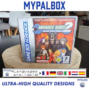 Puede incluir: Una caja de cartucho de juego Game Boy Advance para Advance Wars 2: Black Hole Rising. La caja es azul y blanca con una imagen de los personajes del juego en la parte delantera. El juego está clasificado como 7+ por PEGI.