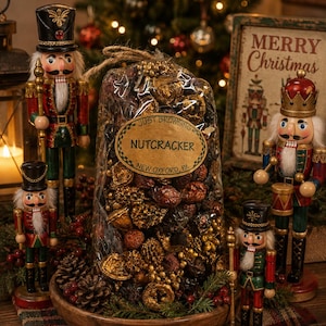 May include: A clear plastic bag filled with gold-painted pinecones, nuts, and dried fruit, featuring an oval label that reads JUST BROWSING NUTCRACKER NEW OXFORD, PA. The bag sits on a wooden bowl surrounded by four wooden nutcracker figurines.