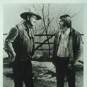 Peut inclure: Photographie en noir et blanc de deux hommes en extérieur. L'un porte un chapeau de cowboy, un gilet et une chemise. L'autre porte une veste et une chemise à carreaux. La photo semble être signée.