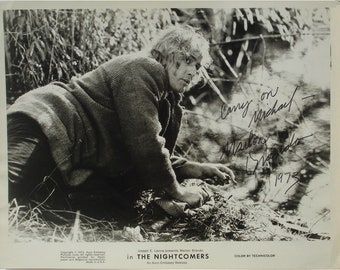 May include: Black and white photo of Marlon Brando in a scene from the movie "The Nightcomers". Brando is wearing a jacket and is crouched down in a forest setting. The photo is signed by Brando with the inscription "Carry on Michael - Marlon Brando 1973".