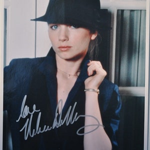 Può includere: Una fotografia in bianco e nero di una donna che indossa un cappello nero e una giacca blu. Sta guardando la telecamera e ha la mano sul mento. La foto è firmata "love, Helen Mirren".