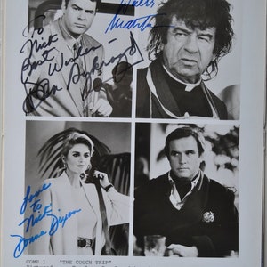 May include: A black and white photo of four actors from the movie "The Couch Trip". The actors are Dan Aykroyd, Walter Matthau, Donna Dixon, and Charles Grodin. Each actor has signed their name in blue ink below their photo.