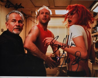 May include: A signed photograph of three people, two men and one woman. The woman has red hair and is wearing a white shirt. The men are wearing red and black shirts. The photograph is signed by all three people.