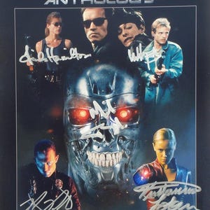 May include: A framed movie poster for "The Terminator Anthology" featuring Arnold Schwarzenegger and other cast members. The poster has multiple signatures and a metallic skull image with red eyes.
