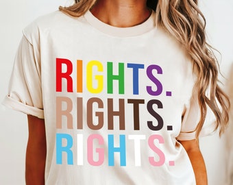 Könnte beinhalten: Ein beiges T-Shirt mit dem Aufdruck "RIGHTS." in Regenbogenfarben. Das Model trägt Größe 2XL.