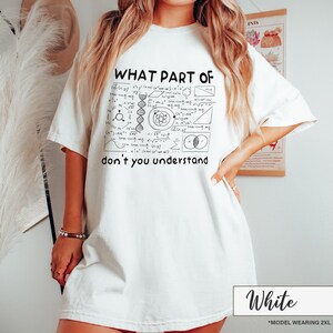 May include: White t-shirt with the text "WHAT PART OF don't you understand" and a black and white graphic of mathematical and scientific symbols. The shirt is a relaxed fit.