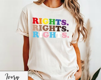 Könnte beinhalten: Ein beiges T-Shirt mit dem dreimal wiederholten Wort "RIGHTS." in Regenbogenfarben. Das Model trägt Größe 2XL.