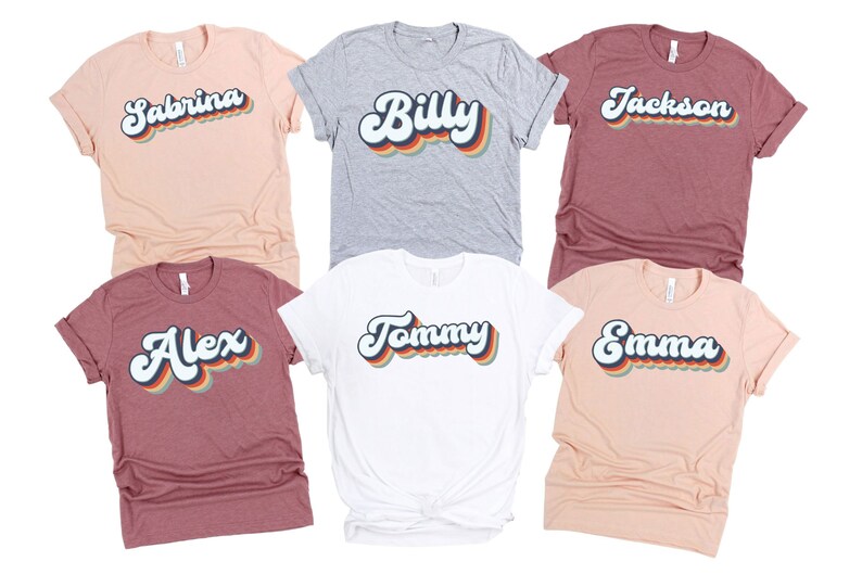 May include: Six t-shirts with different names printed in a retro rainbow font. The names are Sabrina, Billy, Jackson, Alex, Tommy, and Emma.