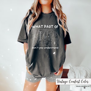 May include: Dark gray t-shirt with the text "WHAT PART OF don't you understand" and a white graphic of mathematical equations and diagrams. The shirt is a vintage comfort color.