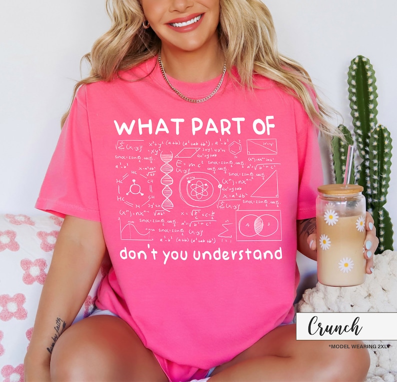 May include: A bright pink t-shirt with the text "WHAT PART OF don't you understand" in white. The shirt features a complex scientific diagram design. The model is wearing a 2XL size.