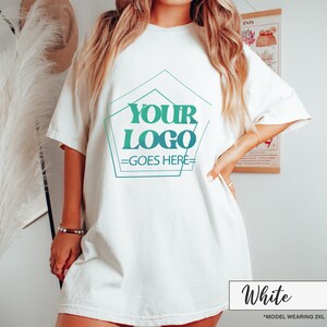 May include: White short-sleeve t-shirt with a teal and green geometric design that reads "YOUR LOGO GOES HERE". The shirt is a relaxed fit. The text "White" is in a white box at the bottom of the image.