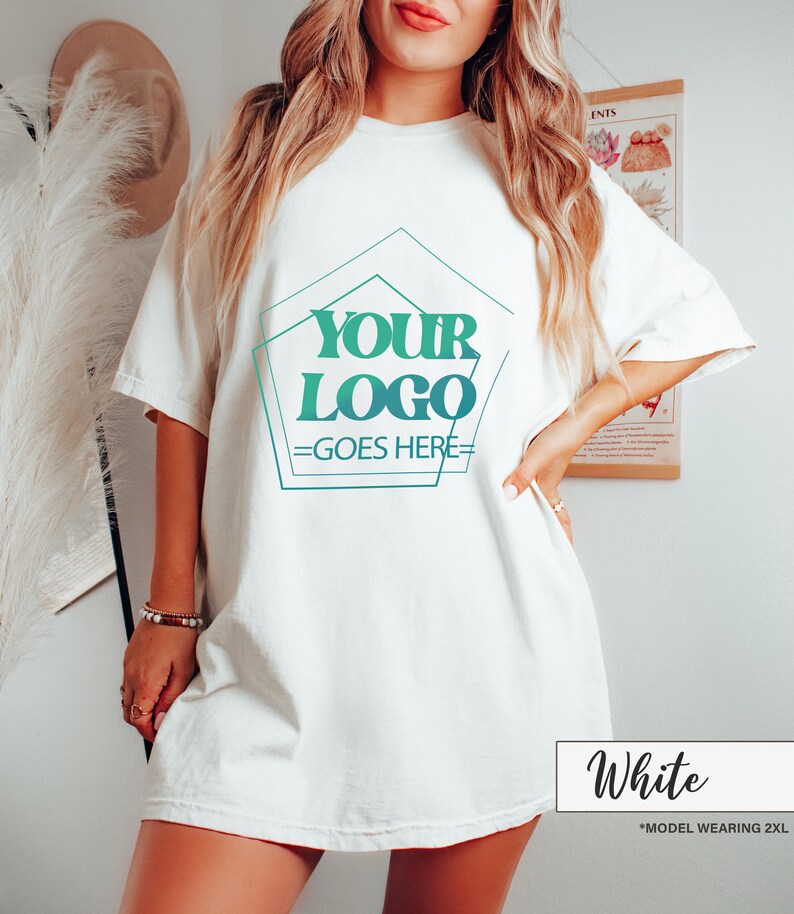 May include: White short-sleeve t-shirt with a teal and green geometric design that reads "YOUR LOGO GOES HERE". The shirt is a relaxed fit. The text "White" is in a white box at the bottom of the image.