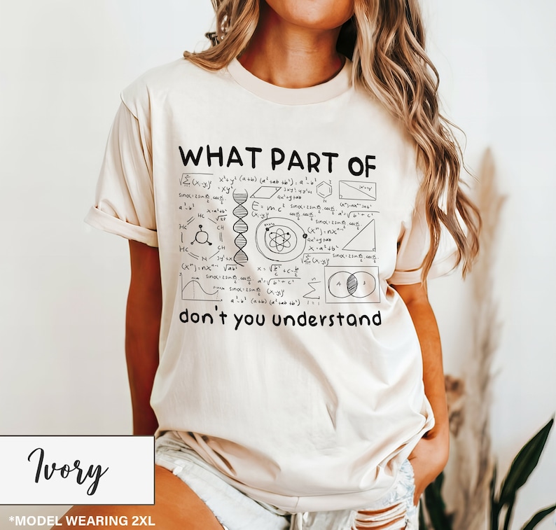 May include: Ivory-colored t-shirt with the text "WHAT PART OF don't you understand" and various scientific diagrams. The shirt is a short-sleeved crew neck.