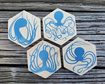 May include: Set of four hexagonal wooden coasters with blue octopus silhouettes. Each coaster features a unique octopus design.