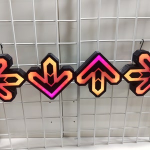 May include: Four black arrow signs with a gradient of orange, pink, and red. The arrows are pointing in different directions: left, down, up, and right.