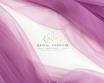 May include: A close-up of a soft, sheer, purple tulle fabric. The fabric is draped and folded, creating a delicate and flowing texture. The fabric is perfect for crafting, sewing, and creating beautiful projects.