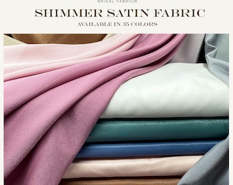 May include: A stack of shimmer satin fabric in various colors, including pink, white, teal, and blue. The image includes the text "Bridal Fabric" and "Shimmer Satin Fabric Available in 35 Colors."