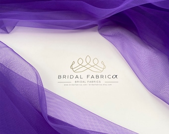 May include: Purple tulle fabric, soft and sheer, with a delicate texture. The fabric is draped over a white surface with the text "BRIDAL FABRICA BRIDAL FABRICS www.bridalfabrica.com | bridalfabrica.etsy.com" and the code "ST55" in the top right corner.