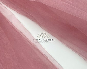 Puede incluir: Primer plano de una tela de tul rosa polvoriento suave. La tela es transparente y tiene una textura delicada. La tela es perfecta para manualidades, costura y decoración.