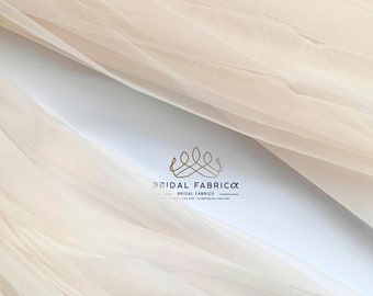 May include: A close-up of a sheer, ivory-colored tulle fabric. The fabric is soft and delicate, with a subtle sheen. The fabric is perfect for creating wedding veils, dresses, and other special occasion garments.