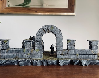 Könnte beinhalten: Ein Miniatur-Steinbogen mit einer grauen Steinmauer und einer kleinen Figur, die im Bogen steht. Der Bogen steht auf einem grauen Steinsockel.
