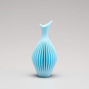 Könnte beinhalten: Eine hellblaue Keramikvase mit einem einzigartigen, gefalteten Design. Die Vase hat einen schmalen Hals und einen breiten, abgerundeten Boden.