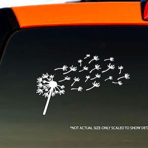 Könnte beinhalten: Weißer Vinyl-Aufkleber mit einem Löwenzahnpflanze, dessen Samen im Wind fliegen. Der Aufkleber befindet sich auf einem schwarzen Autofenster. "NOT ACTUAL SIZE-ONLY SCALED TO SHOW DETAIL" ist unter dem Aufkleber gedruckt.
