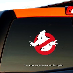 May include: A red and white Ghostbusters no ghost sign with a cartoon ghost in the centre. The sign is on a black car window.