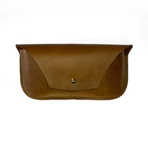 May include: A brown leather glasses case with a gold button closure.