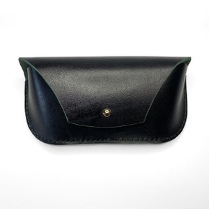 May include: A black leather glasses case with a green lining and a gold button closure.