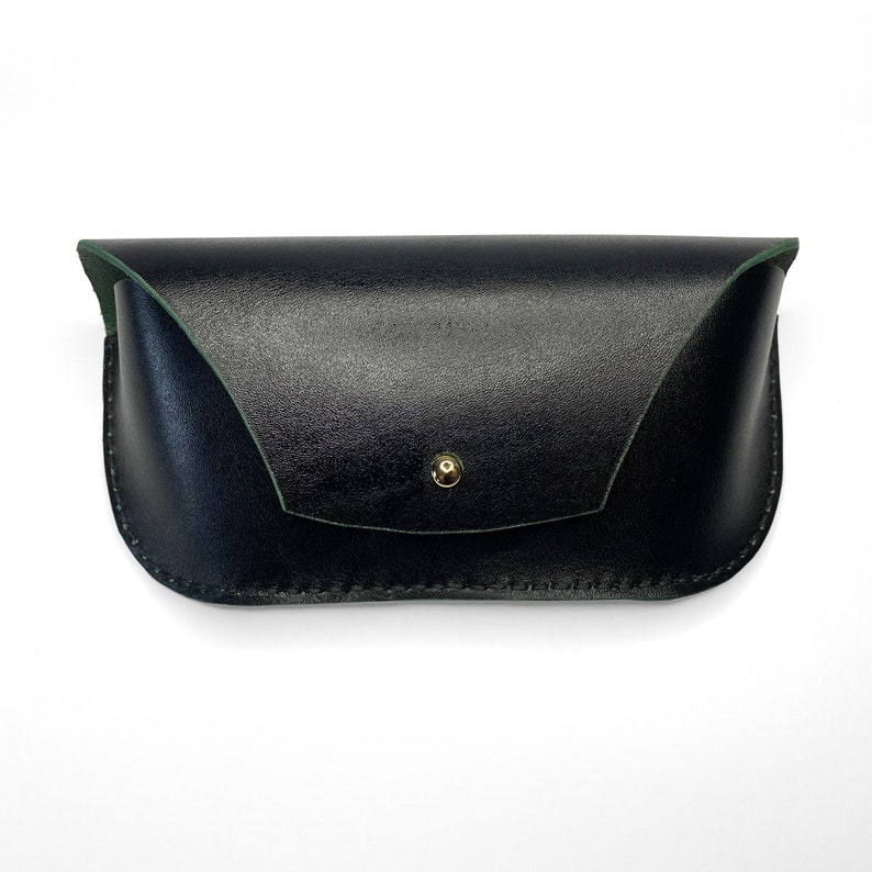 May include: A black leather glasses case with a green lining and a gold button closure.