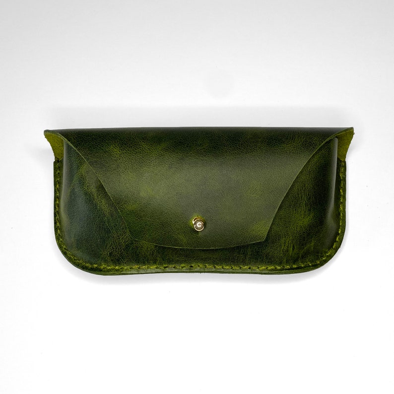 May include: A green leather glasses case with a gold button closure.
