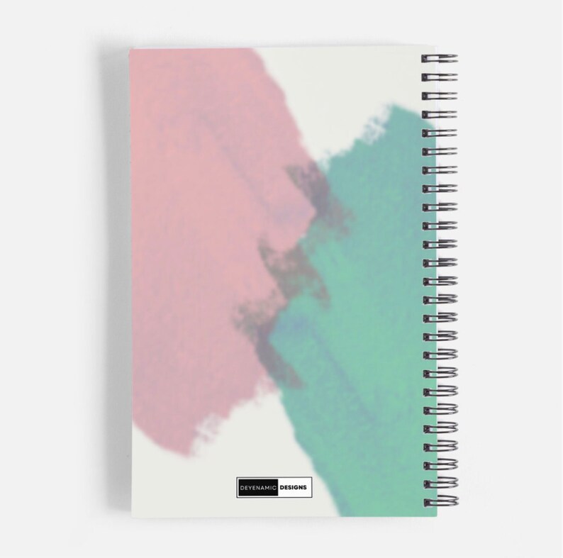 Op de afbeelding: Een spiraalgebonden notitieboek met een witte achtergrond en abstracte aquarelontwerpen in roze, blauw en groen. Het notitieboek heeft de tekst "DEYENVAMIC DESIGNS" onderaan gedrukt.