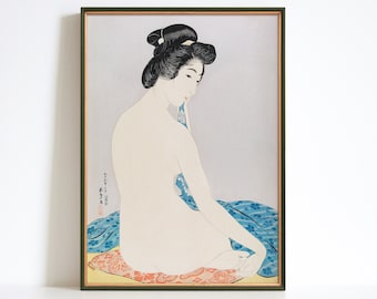 May include: A framed print of a Japanese woodblock print depicting a woman in a blue and white patterned robe sitting on a cushion. The woman has long black hair and is looking down. The print is in a dark green frame.