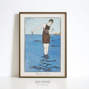 May include: A vintage illustration of a woman in a brown and white swimsuit standing in the ocean. The woman is holding a small object in her hand. The illustration is framed in a gold frame.