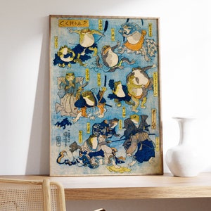May include: A vintage Japanese woodblock print depicting frogs in various poses, some wearing traditional clothing and holding swords. The print is titled "くろたま" and features a blue background with intricate details.