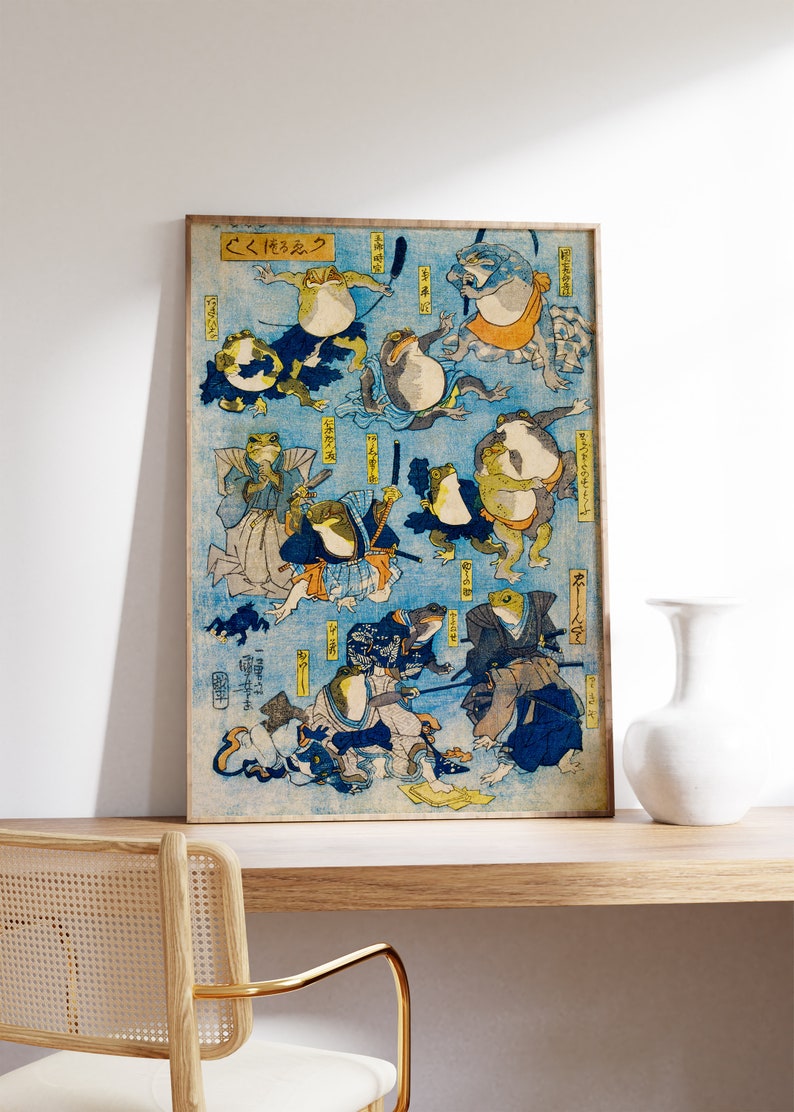 May include: A vintage Japanese woodblock print depicting frogs in various poses, some wearing traditional clothing and holding swords. The print is titled "くろたま" and features a blue background with intricate details.