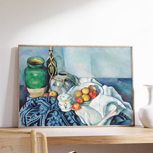 May include: A still life painting featuring a green ceramic vase, a blue and white ceramic pitcher, a white ceramic sugar bowl, and a bowl of red and yellow apples on a blue and white patterned tablecloth.