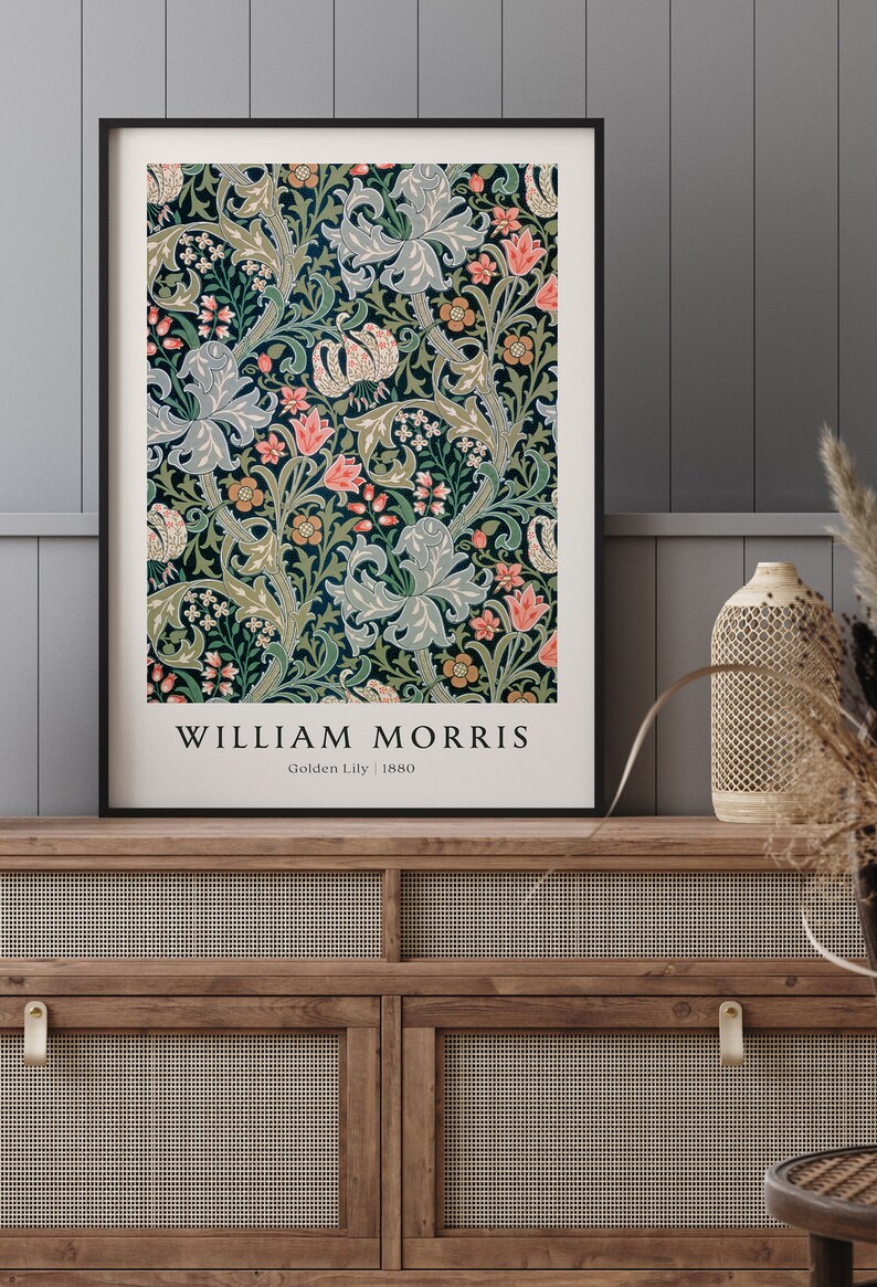 May include: A framed print of a vintage floral pattern by William Morris, titled "Golden Lily" and dated 1880. The design features a repeating pattern of stylised lilies, leaves, and flowers in shades of green, blue, pink, and yellow.