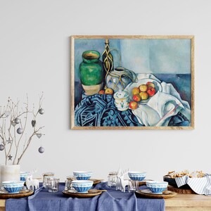 May include: A still life painting of a green vase, a white pitcher, a bowl of apples, and a white cloth on a blue patterned tablecloth.