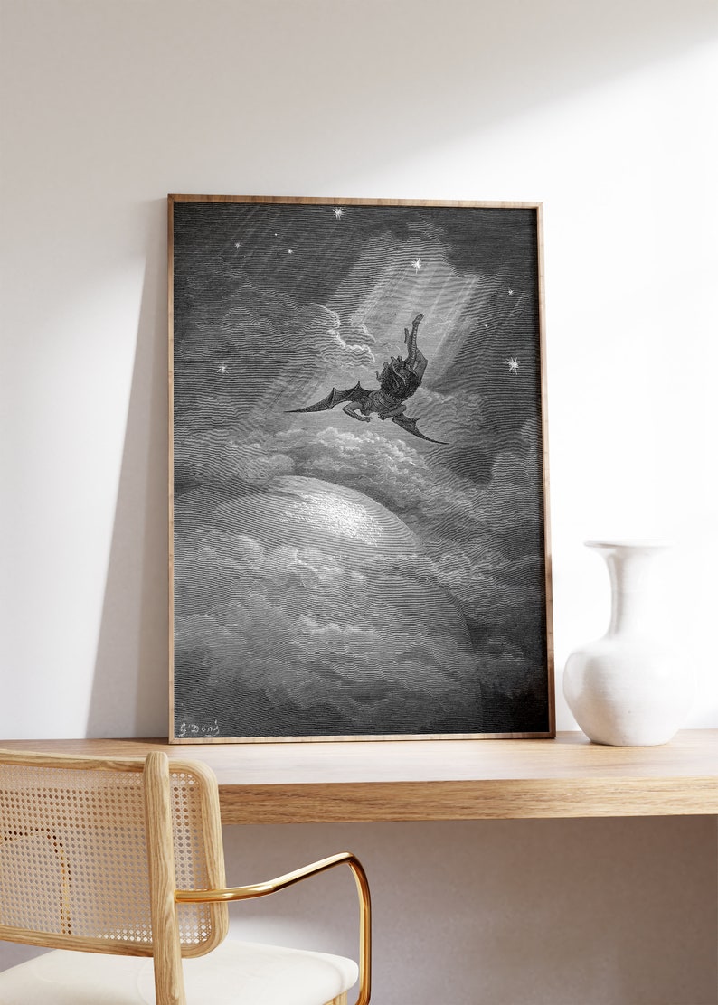 May include: A black and white framed print of a winged figure falling from the sky, surrounded by clouds and stars. The print is set against a white wall and a wooden desk.