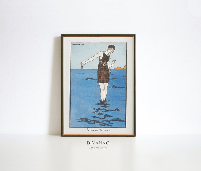 May include: A vintage illustration of a woman in a brown and white swimsuit standing in the ocean. The woman is holding a small object in her hand. The illustration is framed in a gold frame.