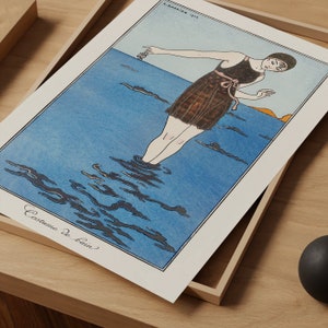 May include: A vintage illustration of a woman in a dark brown swimsuit standing in the ocean. The water is blue and the sky is a light orange. The text "Costume de Bain" is written at the bottom of the image.