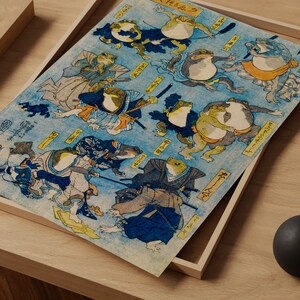 May include: A vintage Japanese woodblock print depicting frogs dressed as samurai warriors. The print features intricate details and vibrant colors, including blue, green, red, and yellow. The frogs are depicted in various poses, holding swords and other weapons. The print is titled "Frog Samurai" in Japanese characters.