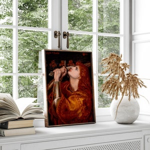 May include: A framed painting of a woman in a red and gold robe holding a sword. The painting is titled "Jehane la Paille" and is set against a dark background.